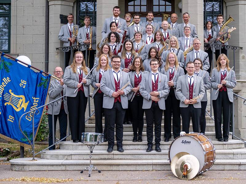 Gruppenbild der Stadtkapelle Gaildorf vor dem Neuen Schloss auf der Treppe mit Trommel, Fahne und Musikern